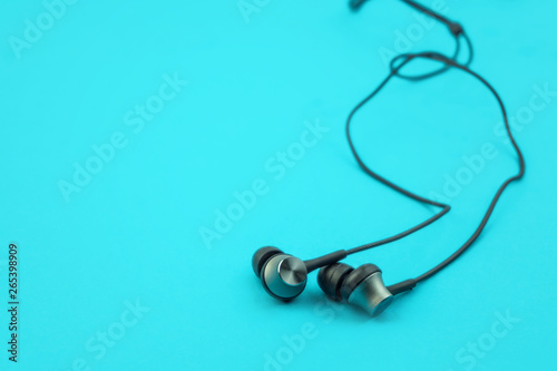 Metal ear buds and wires on blue background, low angle