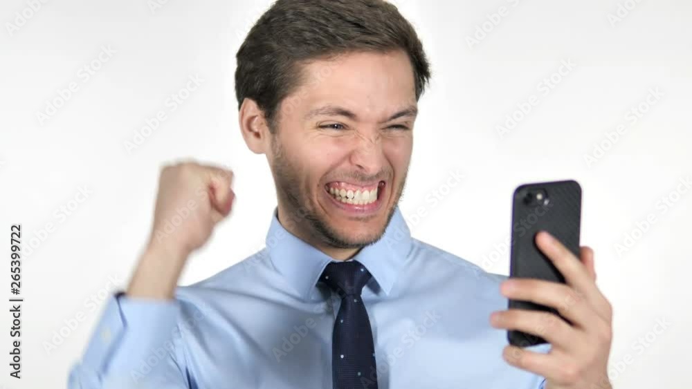 Young Businessman Celebrating Success while Using Smartphone on White Background Young Businessman Celebrating Success while Using Smartphone on White Background