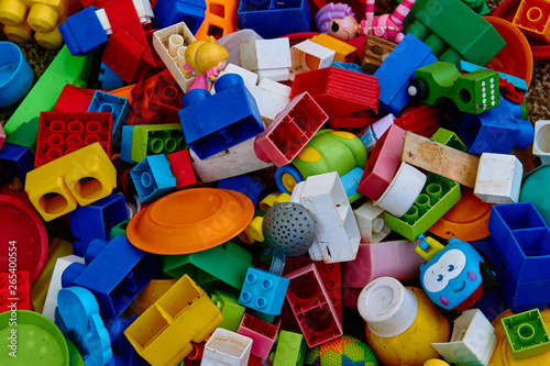 Top view on multicolored toy bricks and other used toys that fill the entire image. Perfect for backgrounds