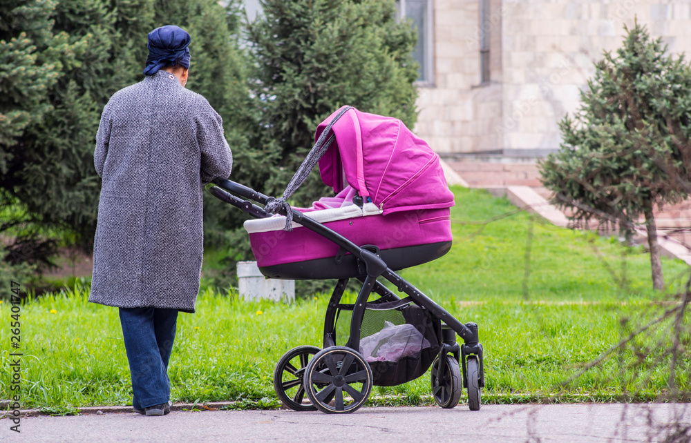 A woman with a stroller on the street with a child. A woman with a stroller on the street with a child.