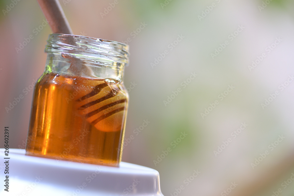Honey healthy food / Close up of yellow sweet honey in jar with wooden dipper Honey healthy food / Close up of yellow sweet honey in jar with wooden dipper