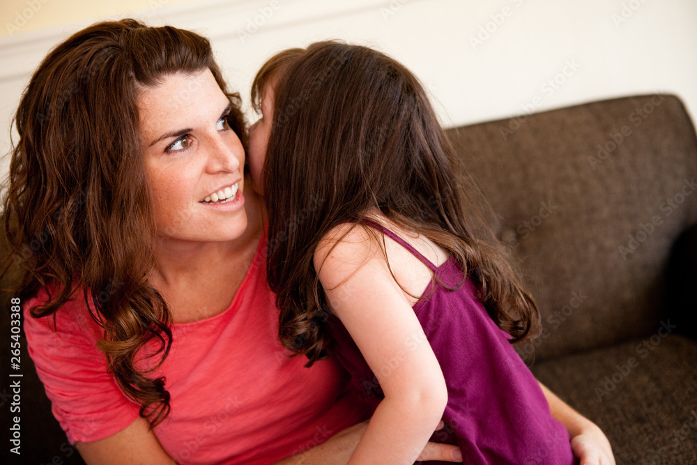Little Girl Whispering a Secret to Mom at Home Little Girl Whispering a Secret to Mom at Home