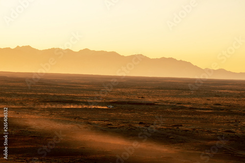 Suvs drive across the vast gobi desert in the early morning hours.