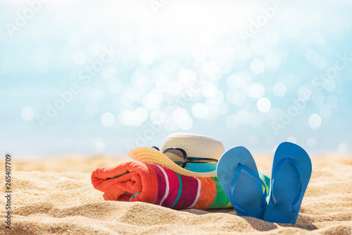 Fototapeta Naklejka Na Ścianę i Meble -  Beach accessories straw hat, flip flops, towel on sunny tropical beach, summer holidays