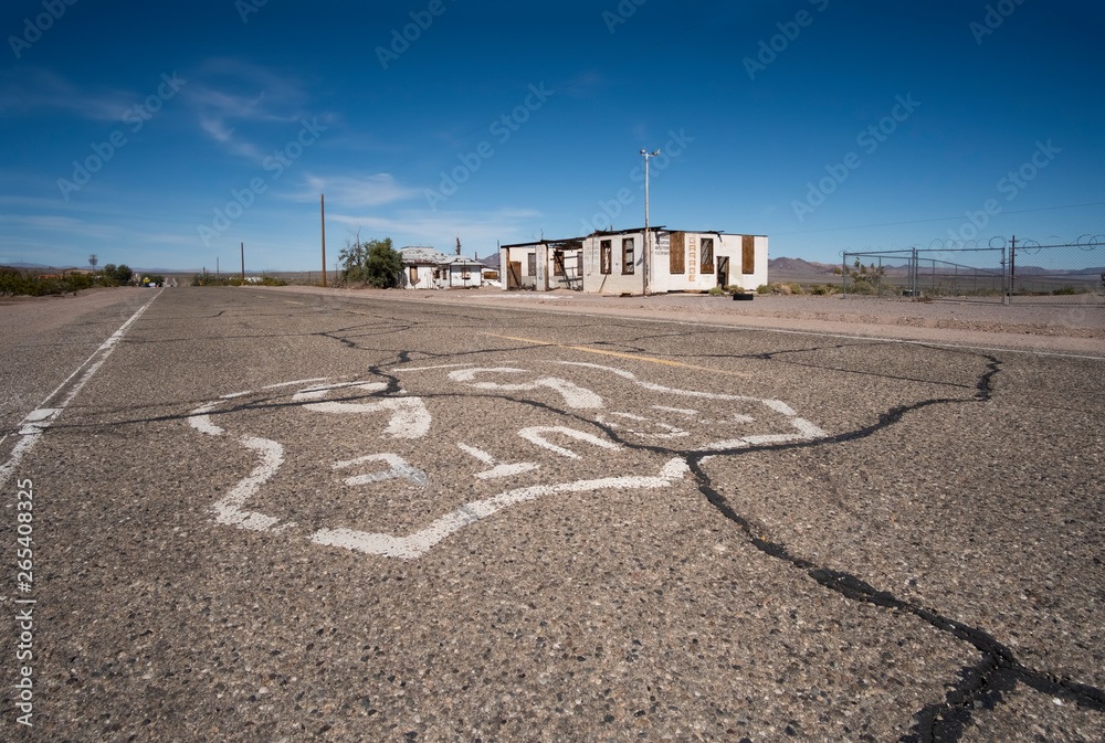 Route 66 with cracked and broken pavement with an abandoned building on the roadside in the background. Route 66 with cracked and broken pavement with an abandoned building on the roadside in the background.