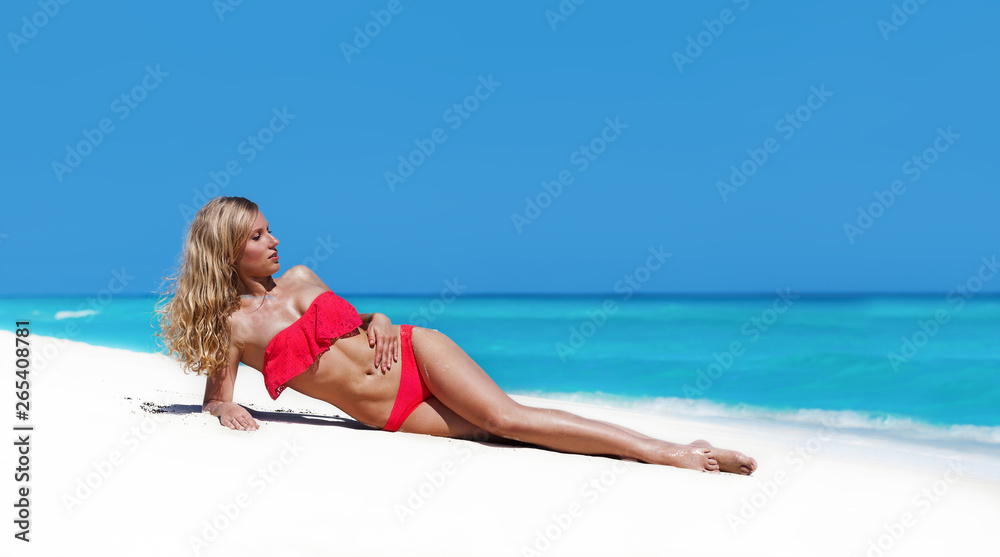 Slim tanning woman with long blond hair lying on tropical beach