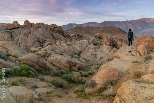 Quadro su tela Asian man photographer and tourist holding DSLR camera looking at view of abstract rock landscape during sunset at Alabama Hills, Lone Pine, California, USA
