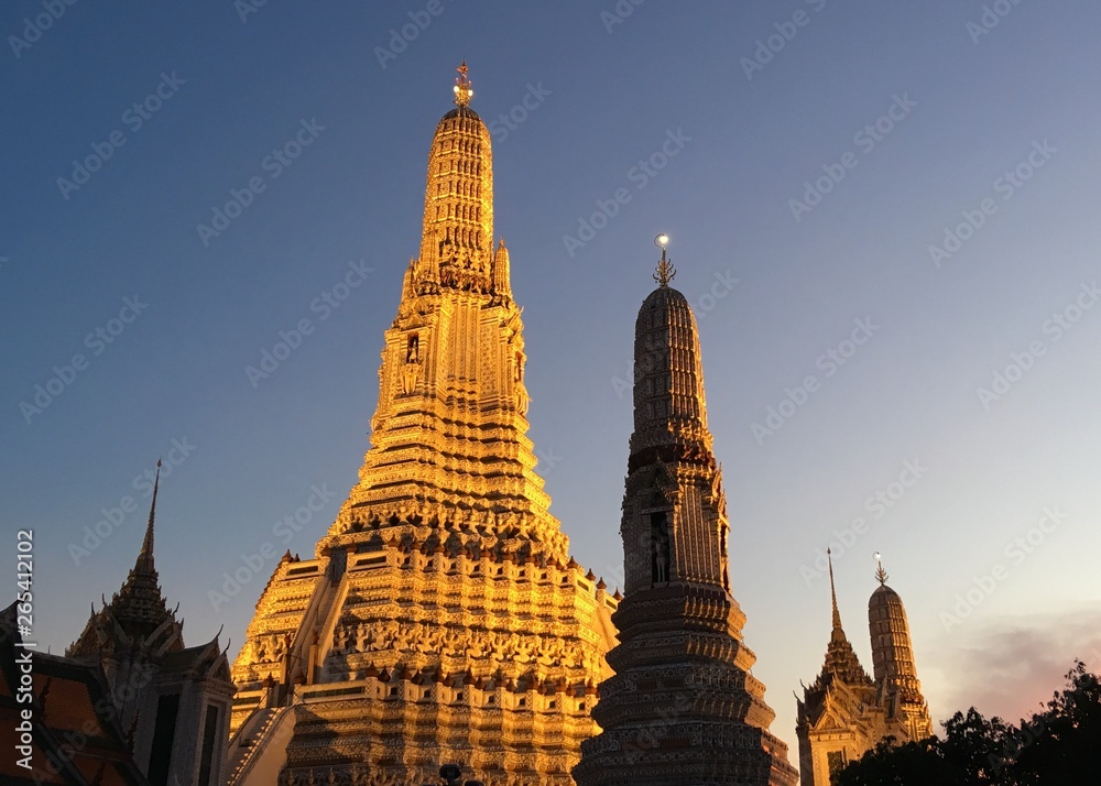 Low angle view of golden pagoda at Wat Arun Ratchawararam temple shining in dark night.