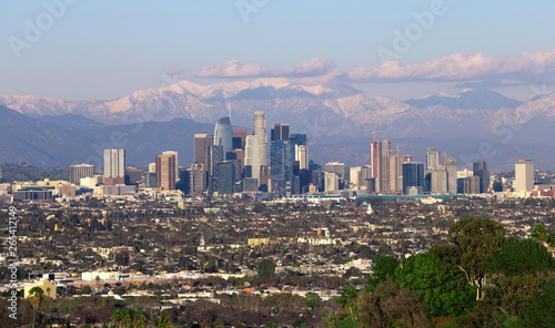 Panoramic view of the city of Los Angeles California with snowy mountain caps showing the end of the drought due to climate change.  The wide view shows Hollywood and Downtown.