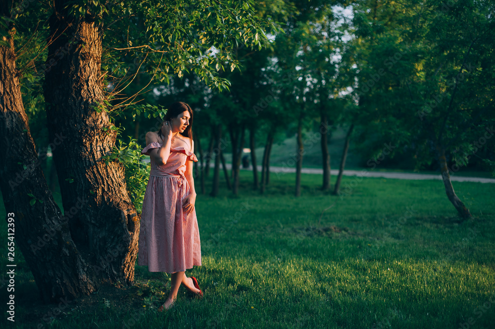 beautiful girl in a red dress under a tree. sunset warm light beautiful girl in a red dress under a tree. sunset warm light
