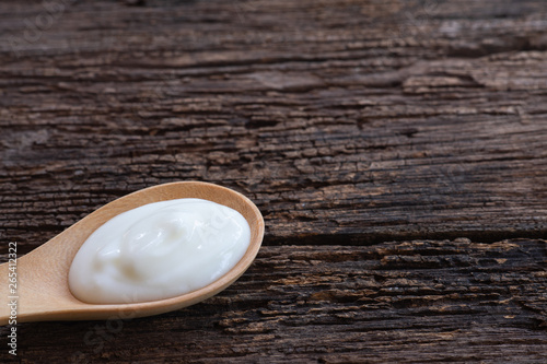 Natural homemade plain organic yogurt in wood spoon on wood texture background