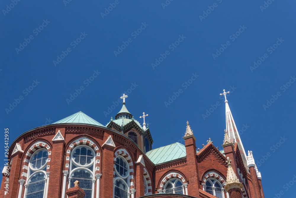 Gothic Revival church with beautiful windows, dome, and spire against a blue sky, horizontal aspect