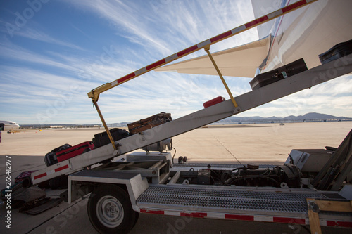 Luggage is being loaded in a passenger plane on a tarmac. Beautiful day at the airport with dramatic clouds.