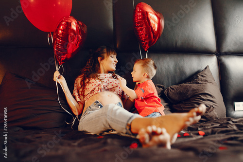 Pregnant woman at home. Mother with son in a bed. Family in a room with decorstions for Valentine's day photo