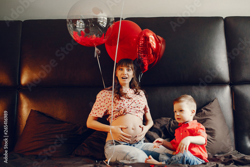 Pregnant woman at home. Mother with son in a bed. Family in a room with decorstions for Valentine's day photo