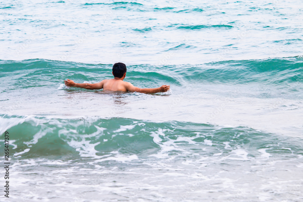 The young man is playing in the sea alone.