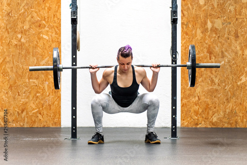 Young girl doing a back squat with a barbell