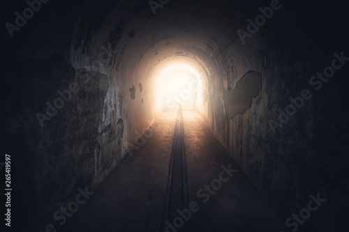 Light in end of tunnel. Long underground concrete corridor in abandoned bunker, toned photo