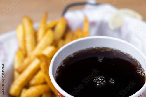 Spicy french fries and cola in red cup, fast food