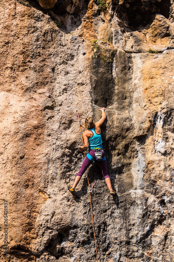 Fototapeta premium A girl climbs a rock.