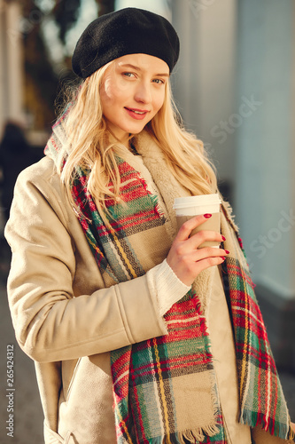 Elegant lady in a winter city. Stylish girl drinking a coffee. Blonde in a cute beret