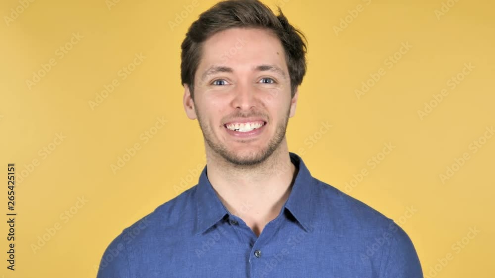 Casual Young Man Waving Hand to Welcome on Yellow Background Casual Young Man Waving Hand to Welcome on Yellow Background