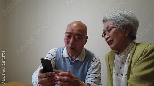 スマホの画面に手を振るおじいちゃんとおばあちゃん