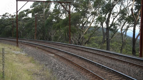 An Intercity communter train passes by on tracks next to the national park, with views of the Megalong Valley, Blue Mountains. photo