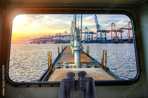 view from window bridge wheelhouse of the incoming ship arrival to an international port for loading discharging and transit the shipment cargo being for logistics system and transport to worldwide