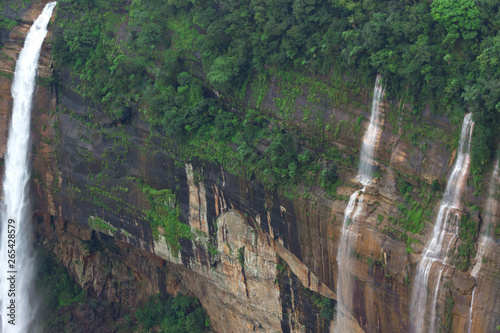 waterfalls falling from a great height rocky mountains overgrown jungles and cloud-covered photo