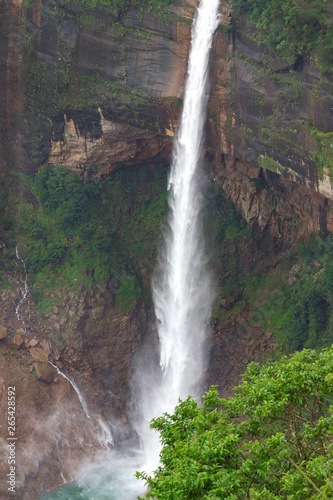 waterfall falling from a great height rocky mountains overgrown jungles and cloud-covered