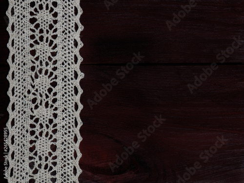 White laces on a brown wooden background vertically