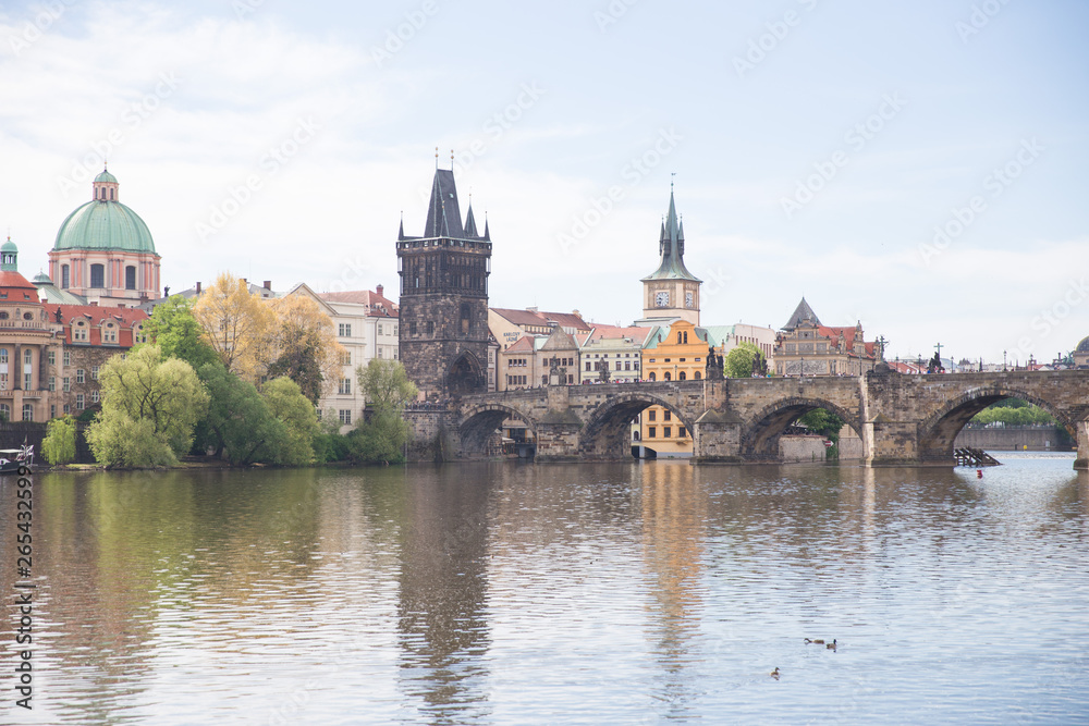 Old Charles bridge and buildings. Vltava river with glare. Travel photo 2019.