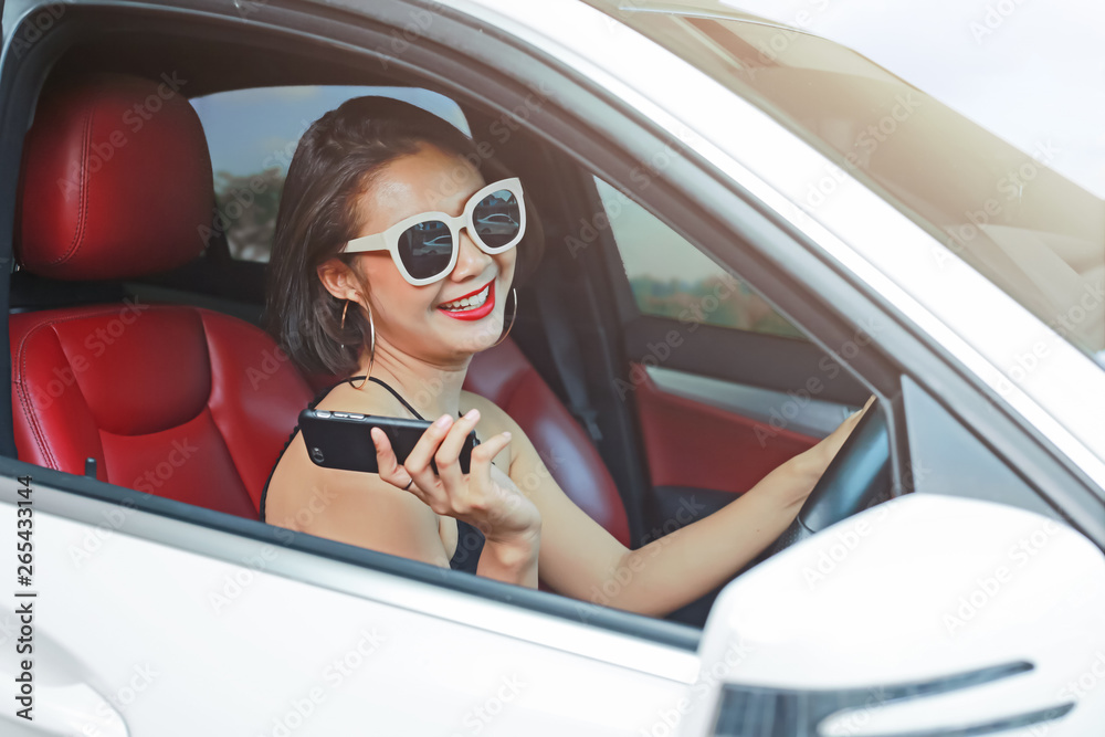 Young woman driving the car and talking phone on the road.