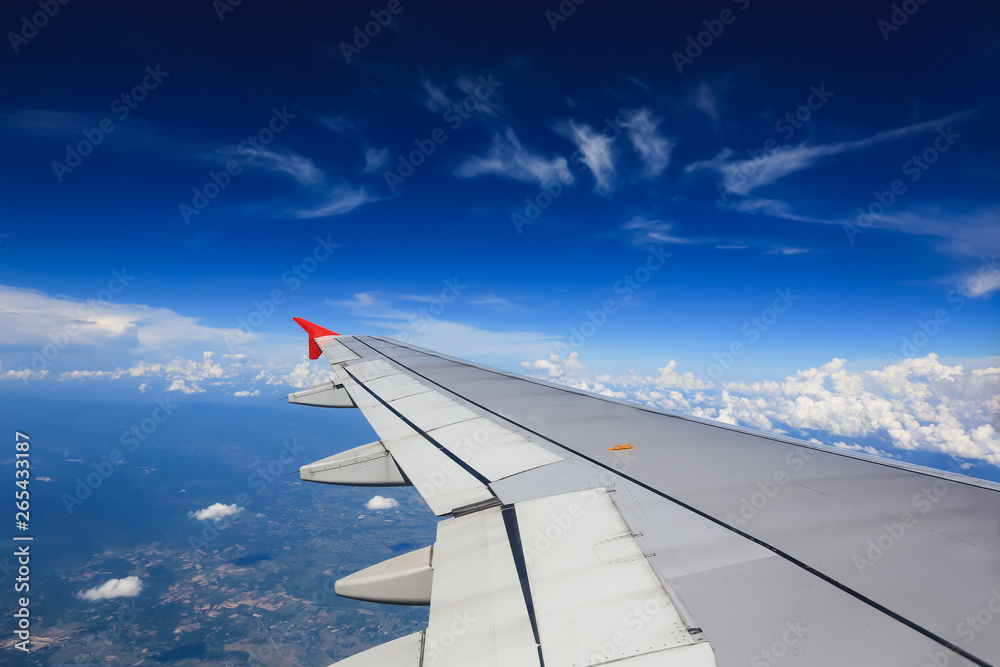 Fototapeta premium Wing of an airplane flying above in the morning clouds.