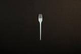 White plastic fork on a black background. Concept plastic, harmful, environmental pollution, stop plastic. Flat lay, top view.