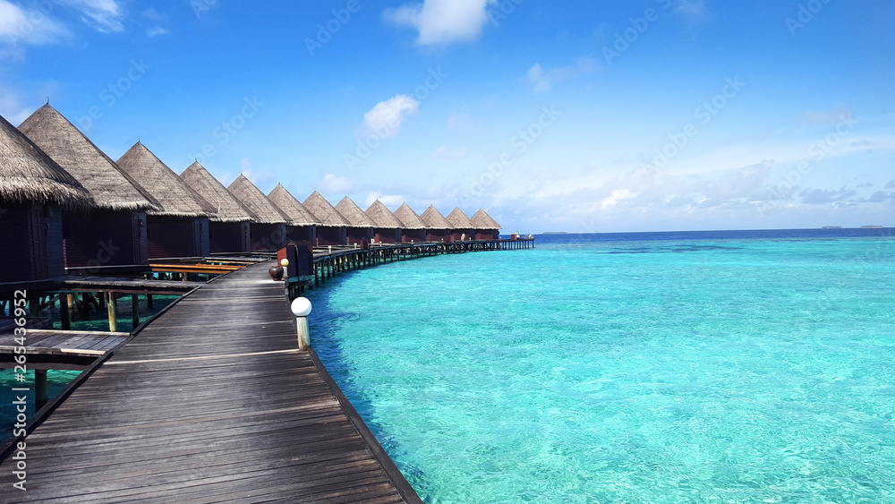 Water villa and the wooden bridge above turquoise color water sea at Maldives island for summer holiday destination concept. Water villa and the wooden bridge above turquoise color water sea at Maldives island for summer holiday destination concept.