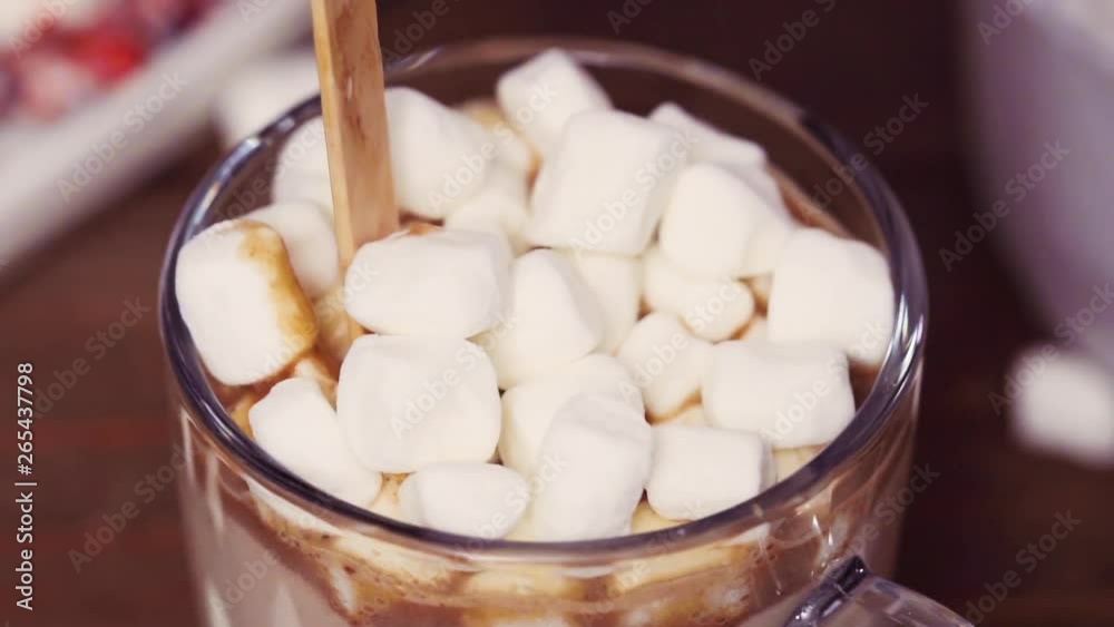 Slow motion. Close up. Salted caramel hot cocoa spoon in glass cup topped with marshmallows. Slow motion. Close up. Salted caramel hot cocoa spoon in glass cup topped with marshmallows.