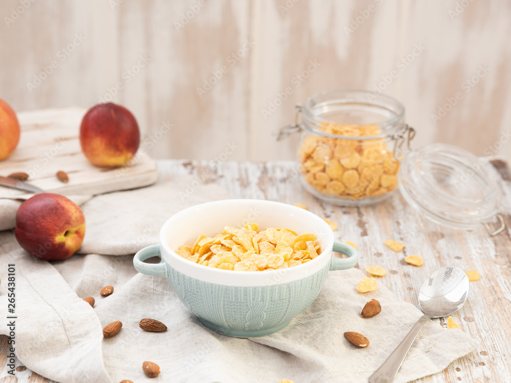 Bowl with cornflakes, peaches and almonds nuts. Healthy cereal breakfast on wooden table Bowl with cornflakes, peaches and almonds nuts. Healthy cereal breakfast on wooden table