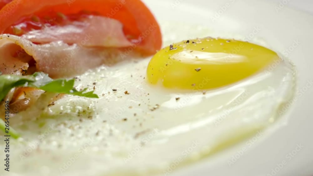English breakfast. Close-up shot of three fried eggs and bacon serving on a white plate. Slow motion. HD English breakfast. Close-up shot of three fried eggs and bacon serving on a white plate. Slow motion. HD