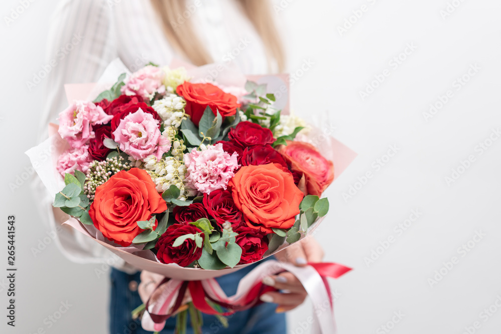 Beautiful bouquet of mixed flowers in womans hands. the work of the florist at a flower shop. Delicate Pastel color. Fresh cut flower. Red and pink color
