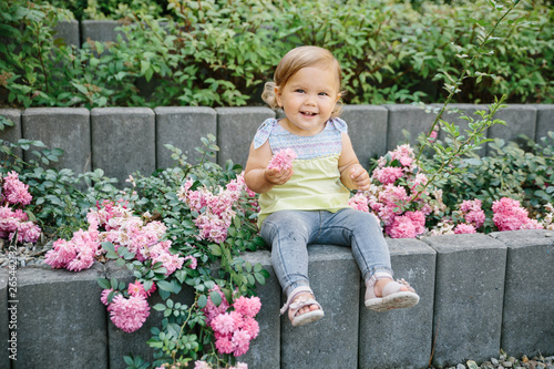 Baby girl outside playground laughing in flowers © tmelnikova