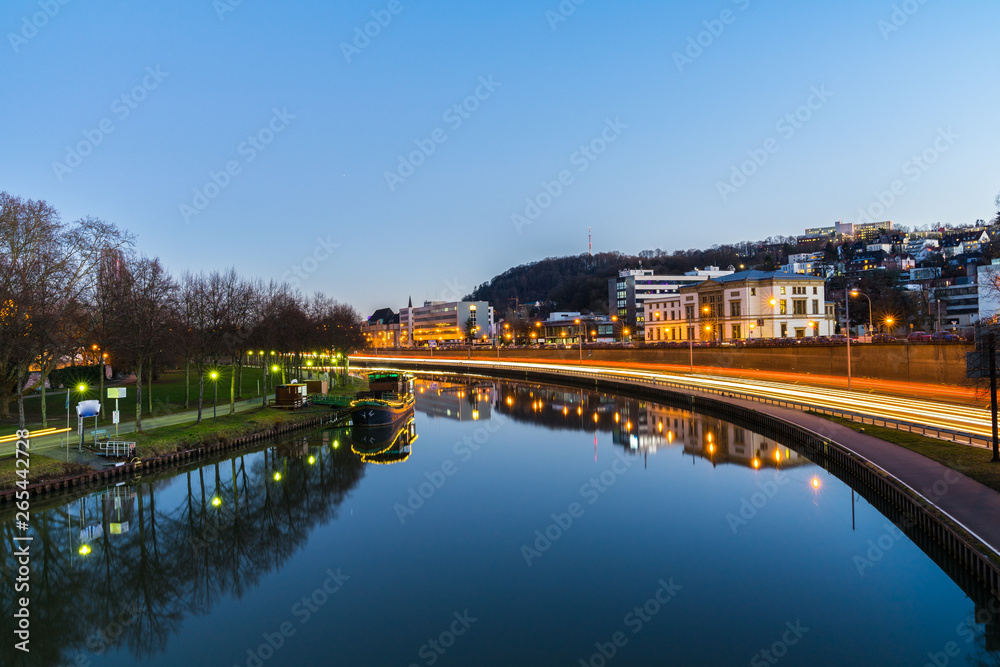 Germany, City saarbrucken night traffic and buildings reflecting in saar river water in magic atmosphere