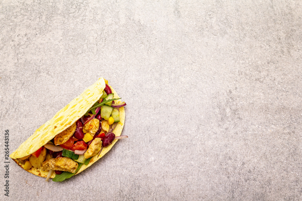 Mexican taco with chicken meat, red beans, fresh vegetables. Latin american food, stone background, copy space. Mexican taco with chicken meat, red beans, fresh vegetables. Latin american food, stone background, copy space.