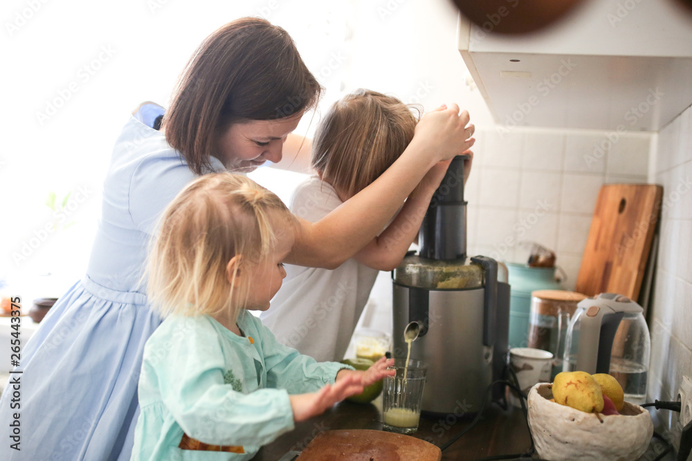 Mother and children cut apples and squeeze juice