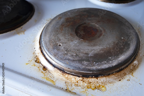 Contaminated white old electric stove with soot around the electric hot plates close up