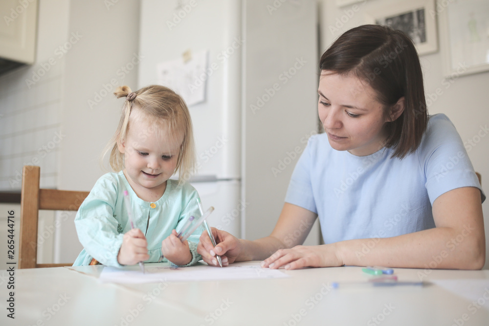 Mom and cute blonde girl in dresses paint together Mom and cute blonde girl in dresses paint together