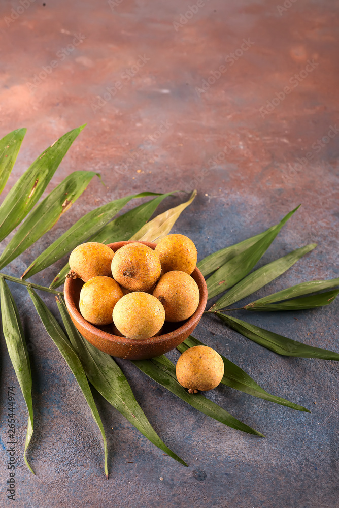 Tropical fruit longan in the bamboo basket on stone background