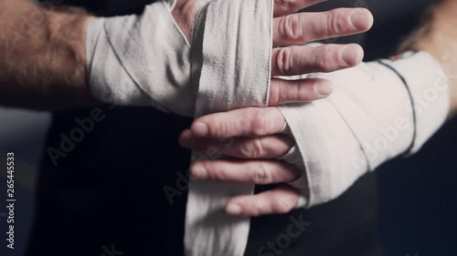 Close up, boxer wrapping hands with elastic bandages before fight, slow motion