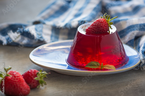 Photo of fruit jelly with fresh strawberry. Healthy food. Strawberry jelly on white plate. Summer dessert with fruit jelly and fresh strawberry.